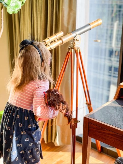 A young girl looks through a telescope at the Chicago skyline.