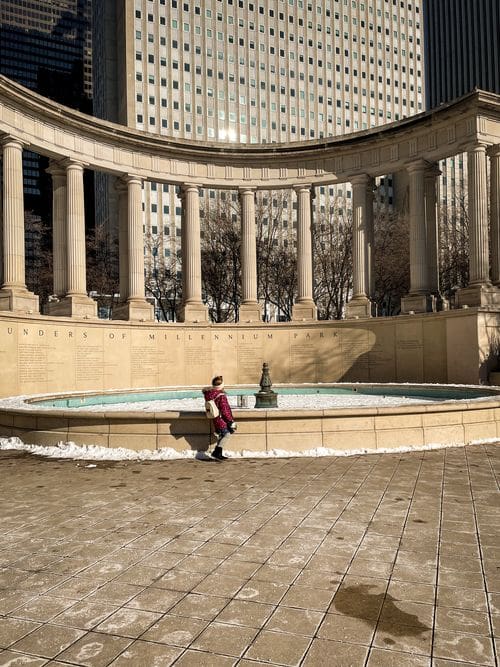 A young girl stands in front of an empty fountain in Millennium Park during the winter.
