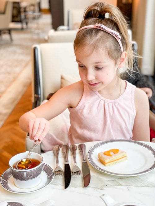 A young girl stirs her tea while enjoy the Afternoon Tea experience at The Langham, Chicago.