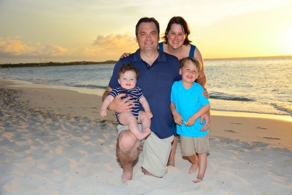 A family of four stands together on the beach, while staying at Beaches Turks and Caicos.