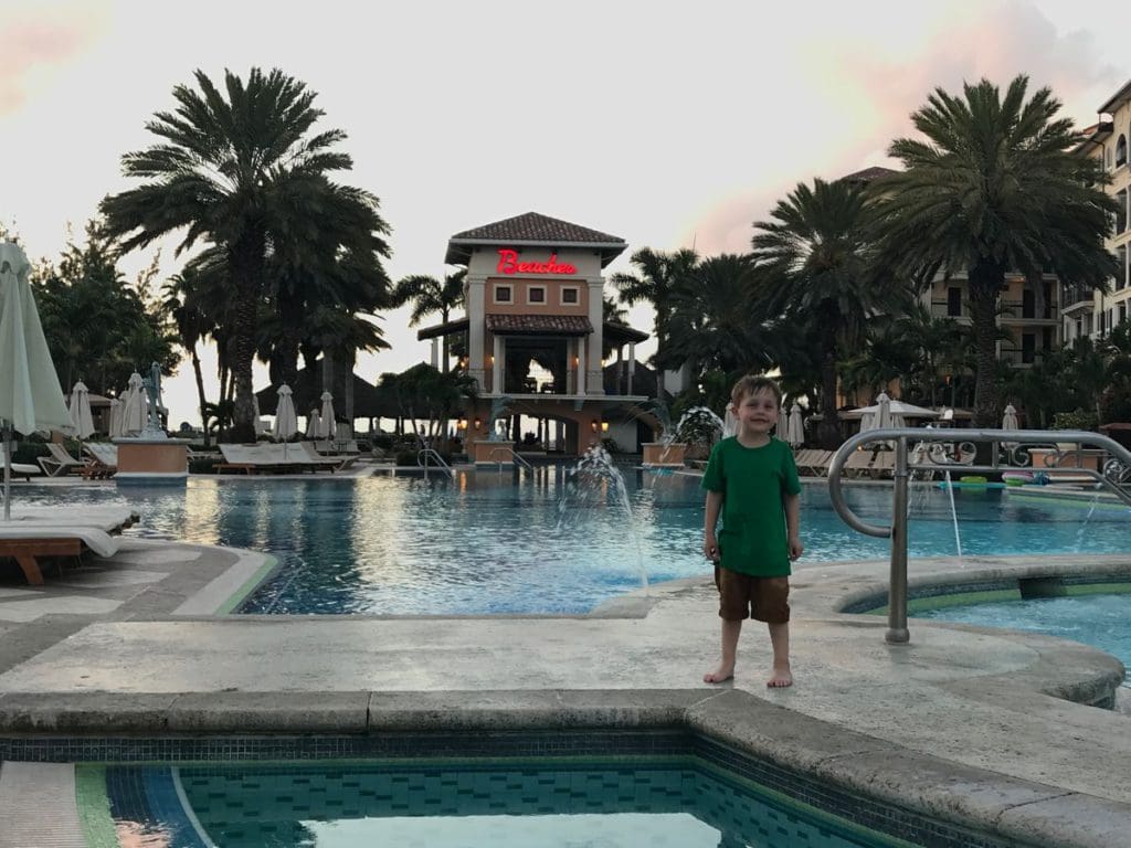 A young boy stands on a pool deck at a Beaches resort.