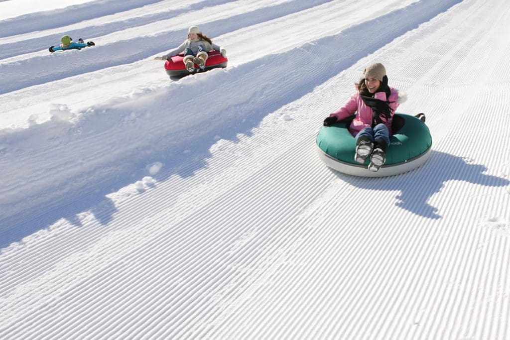 Three kids snow tube down the lanes at Bear Creek Mountain Resort.