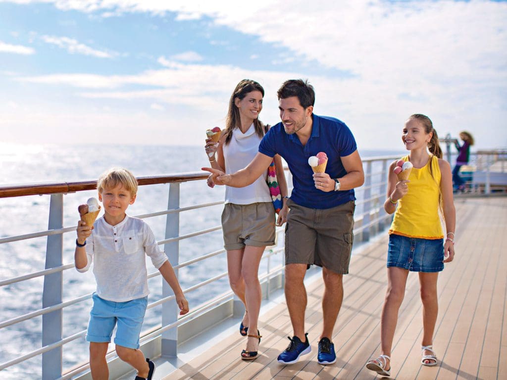 A family of four eating ice cream cones, walks across the top deck of a Costa Cruises ship, one of the best cruise lines for families.