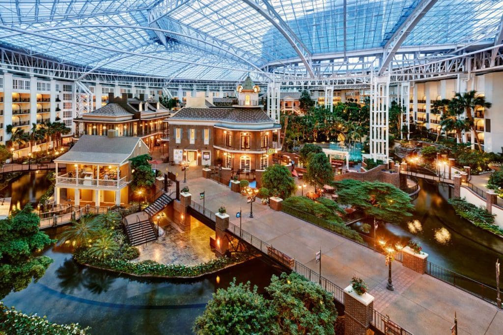 Inside the atrium of the Gaylord Opryland Resort & Convention Center, featuring lush greenery, cozy lighting, and a broad walkway.