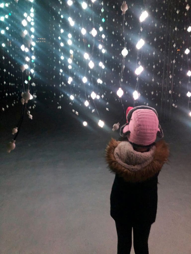 A young girl enjoys peering at the Snowmass Luminescence experience. 