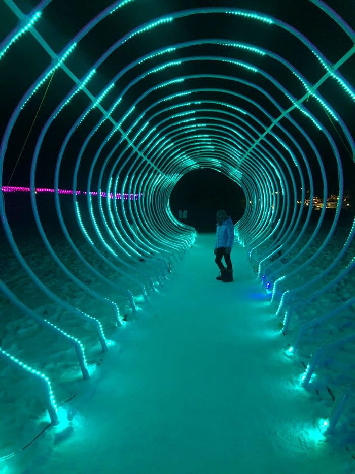 A young boy walks through a tunnel of green lights at the Snowmass Luminescence.