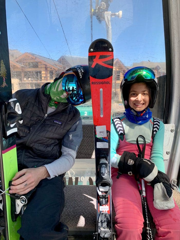 Two kids sit on a chair lift ready to ski at Aspen Mountain.