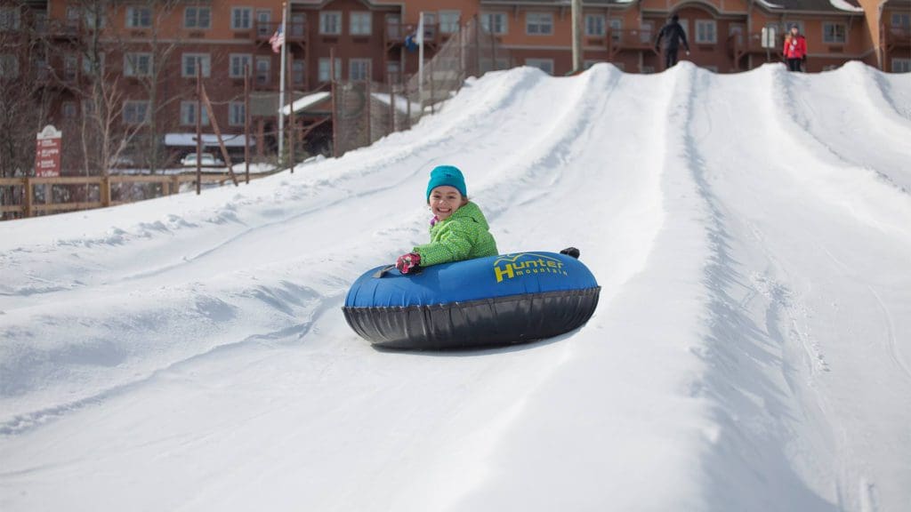 A young girl smiles as she flies down the hill on a snow tube at Hunter Mountain Resort.