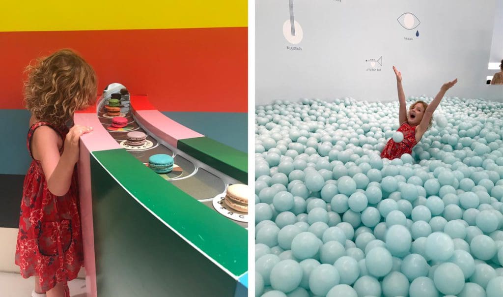 Left Image: A young girl looks into a colorful exhibit at the Color Factory. Right Image: A young girl dances in an exhibit at the Color Factory filled with light blue balls.