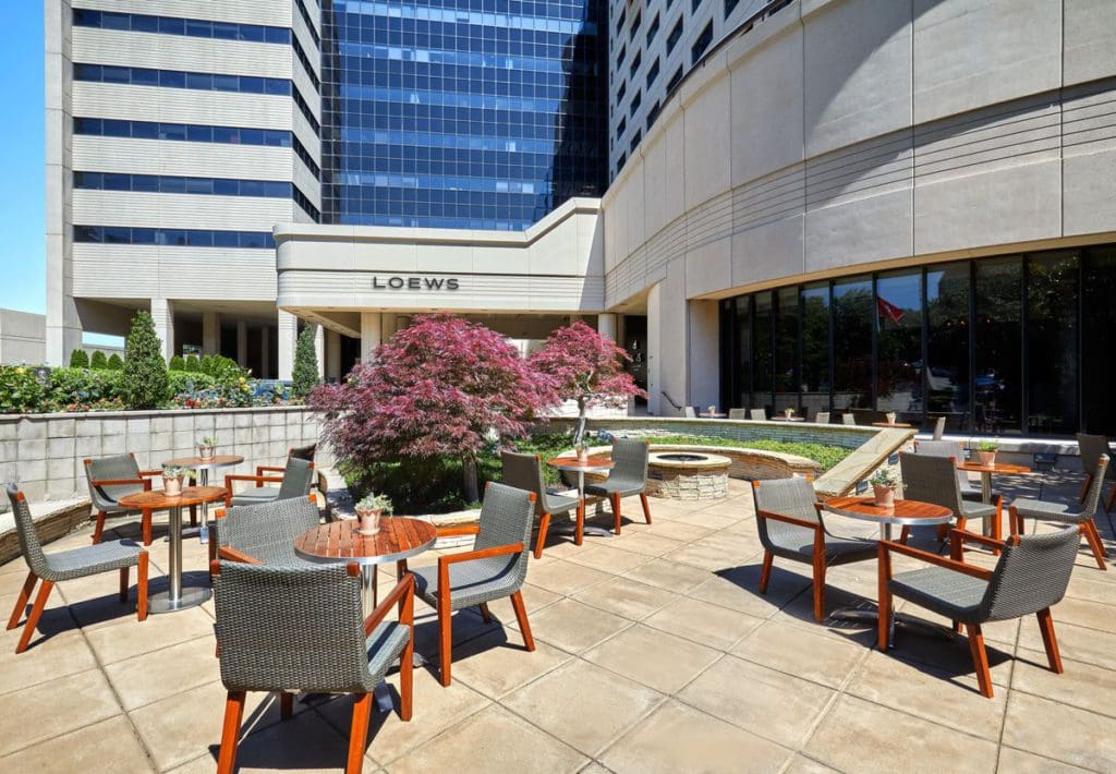 The outdoor patio at the Loews Vanderbilt Hotel, one of the best Nashville hotels for families, featuring several chairs and tables, on a sunny day.