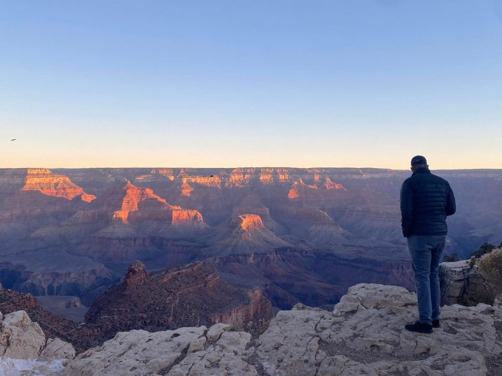 A man stands at the edge of the Grand Canyon at sunset, one of the best things to do on this Sedona and Grand Canyon itinerary for families.