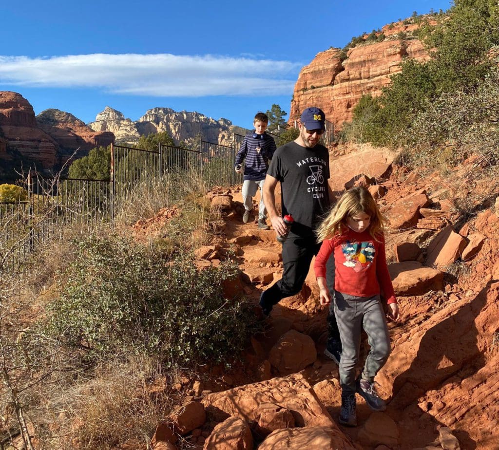 A dad and his two daughters hike down a trail near Sedona.