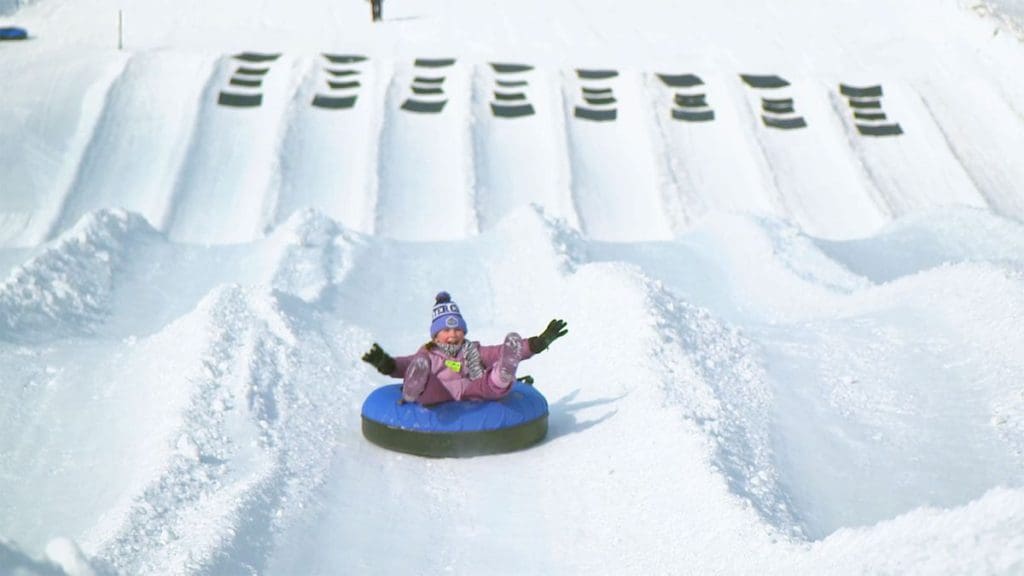 A young child flies down the snow tubing hill at Montage Mountain on a winter day.