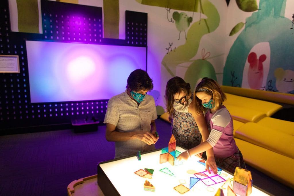 Three kids play at an exhibit at the Oregon Museum of Science and Industry.