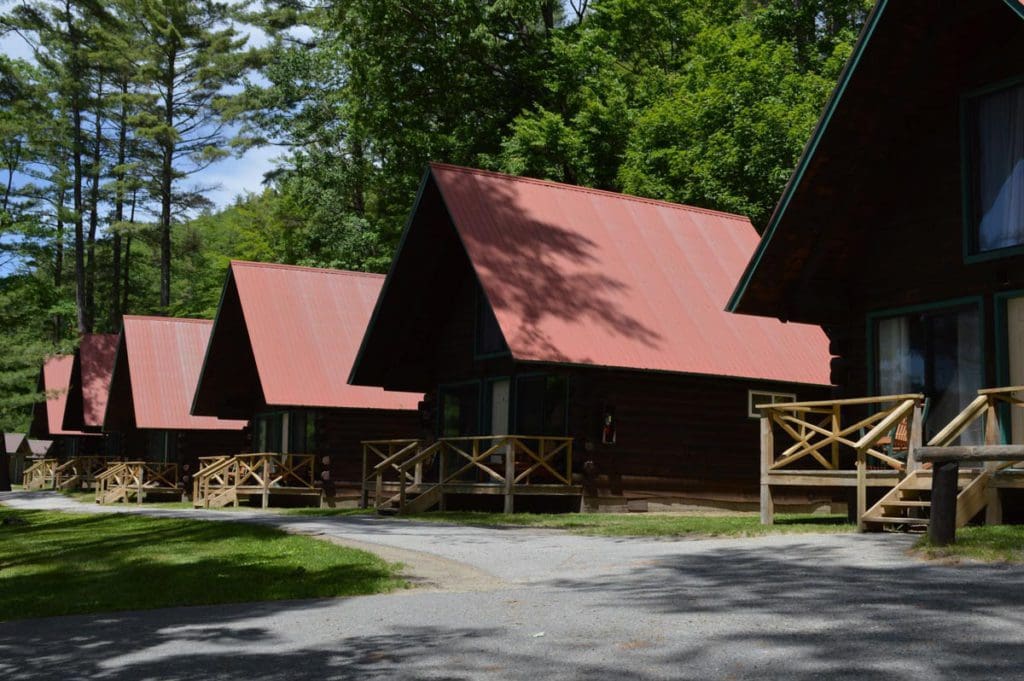 A row of rustic cabins, with red roofs, amongst the trees at Photo Courtesy: Ridin-Hy Ranch Resort.