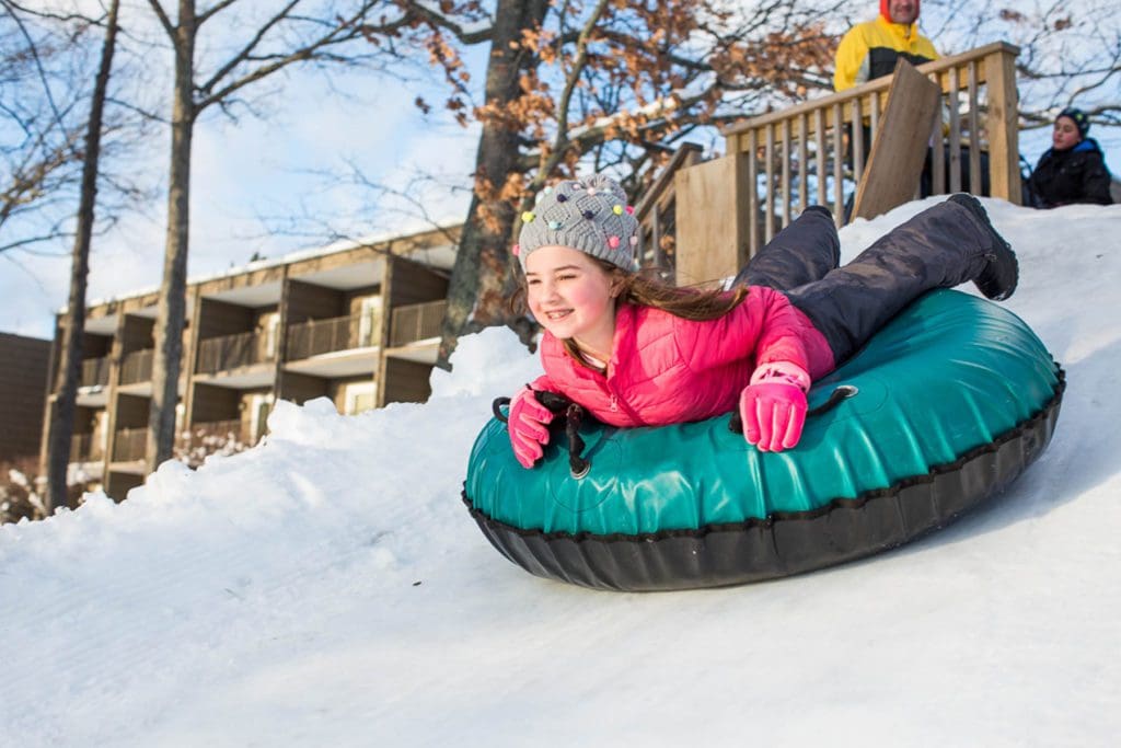 A young girl slides down a hill on a snow tube at Woodloch Resort, one of the best hotels with snow tubing near NYC for families.