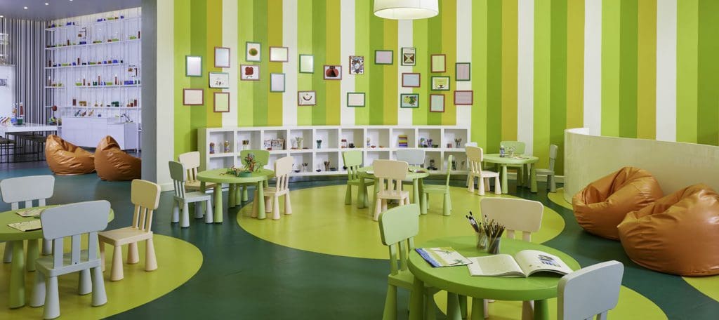 Inside the kids' club at the Azul Beach Resort Negril, featuring lime green and white furnishings, with several cozy places to play.