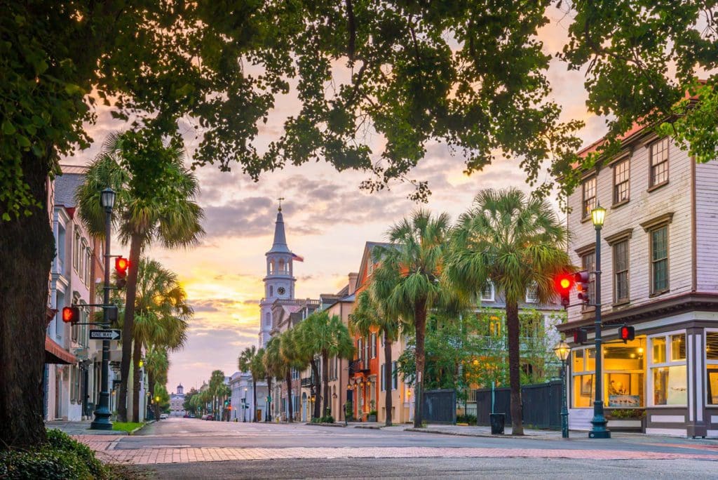 The main street in Charleston, South Carolina, with a large church at the end of the street, at dusk.