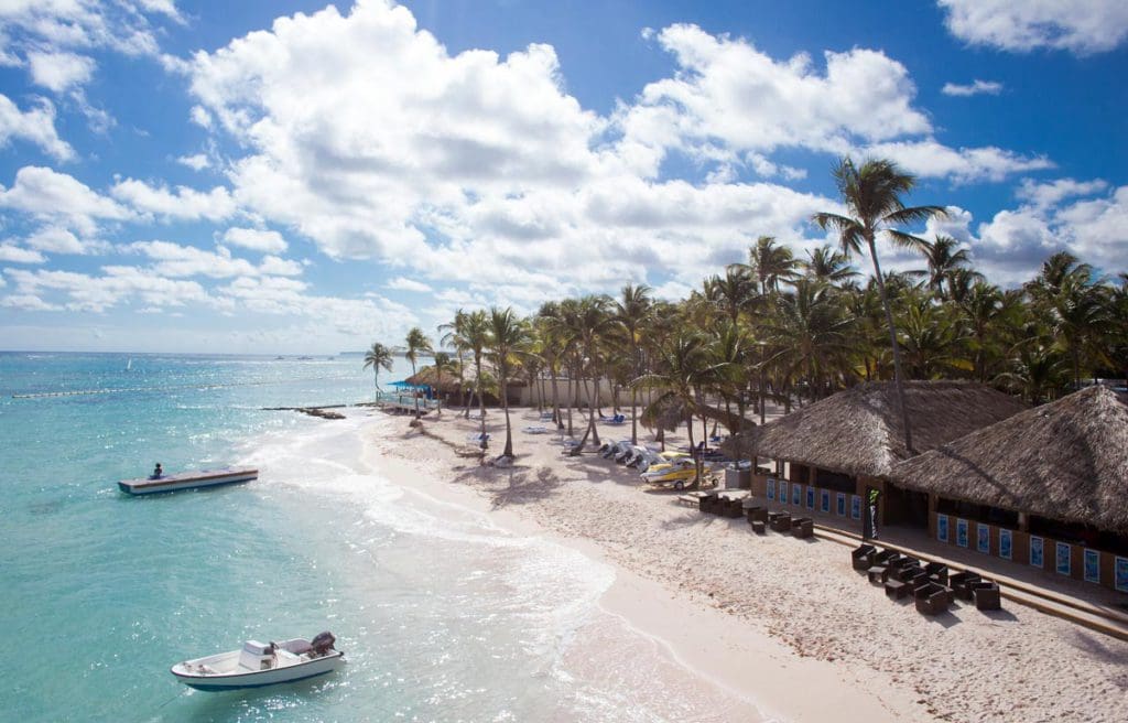 The beach and nearby cabanas at Club Med Punta Cana, while two boats are stationed in the water.