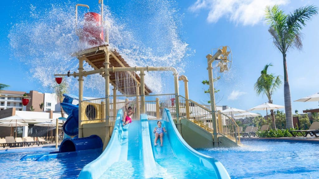 Children rush down a waterslide at the on-site pool at .Hyatt Ziva Cap Cana, one of the best all-inclusive resorts in the Caribbean for families.