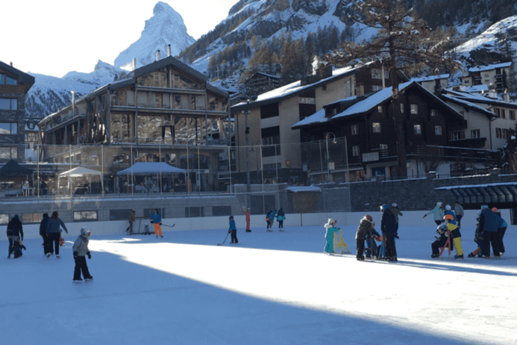 Several people skate around an outdoor ice rink in Zermatt.