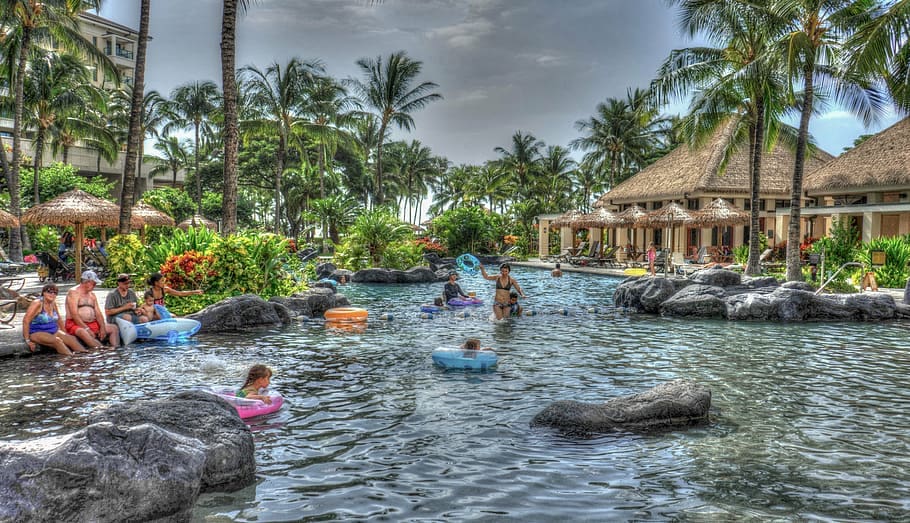 Several kids play in the pool at Marriott's Ko Olina Beach Club, with cabanas and palm trees flanking the pool.