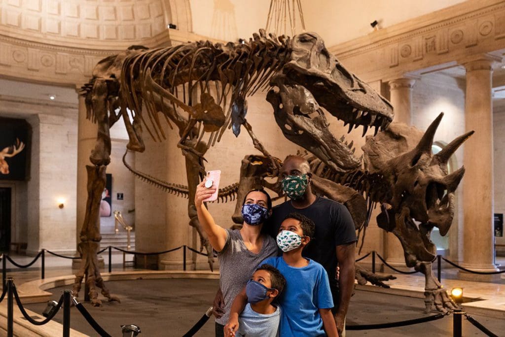 A family of four takes a selfie in front of two dinosaur skeletons at the Natural History Museums of Los Angeles County.