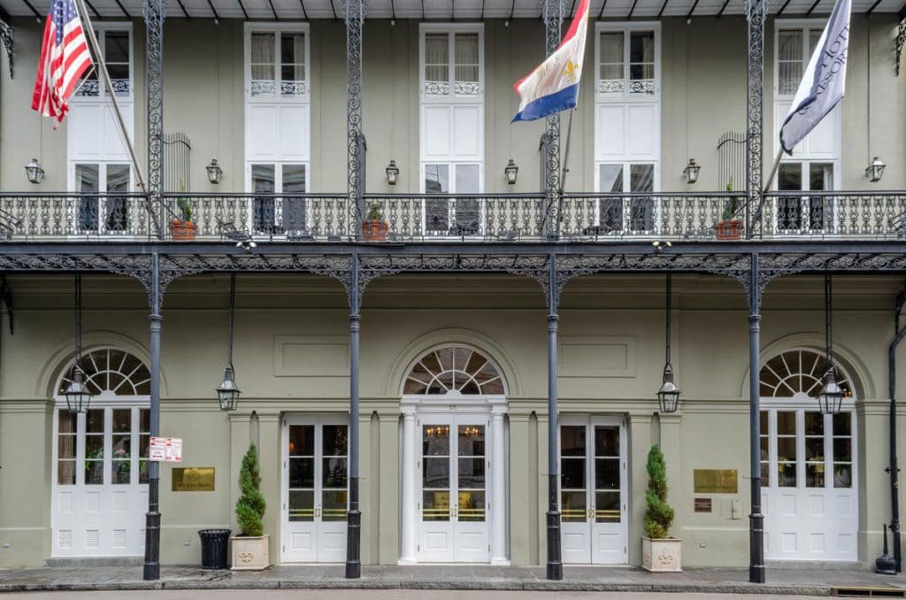 The exterior entrance to Omni Royal Orleans, featuring New Orleans architecture and swaying flags along the balcony.
