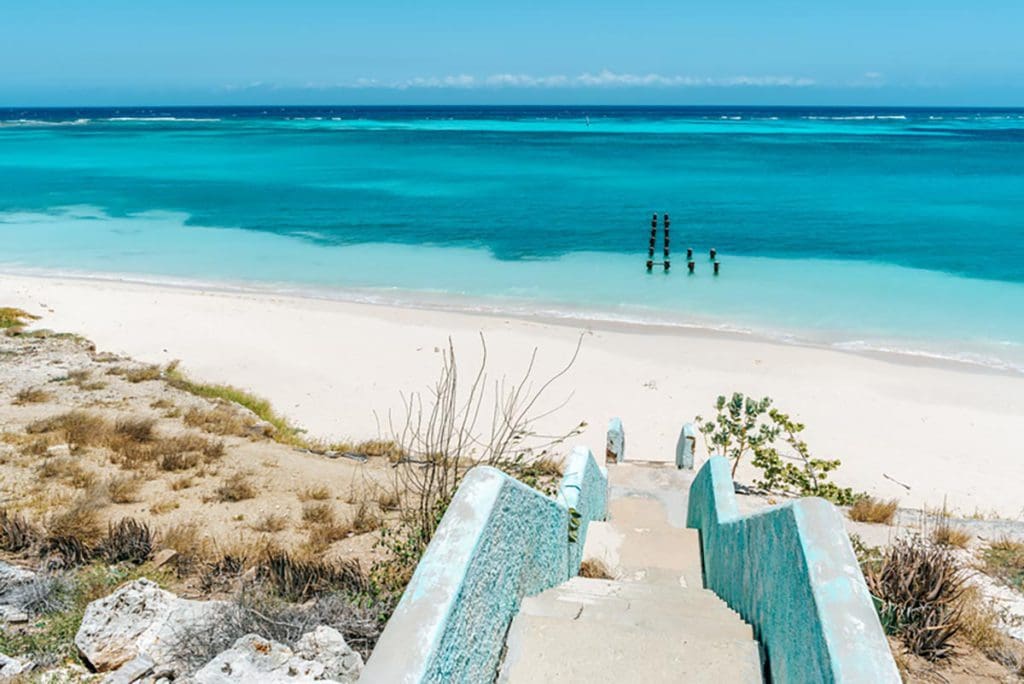 A descending staircase onto Rodgers Beach, featuring white sands and turquoise waters at one of the best beaches in Aruba for families.