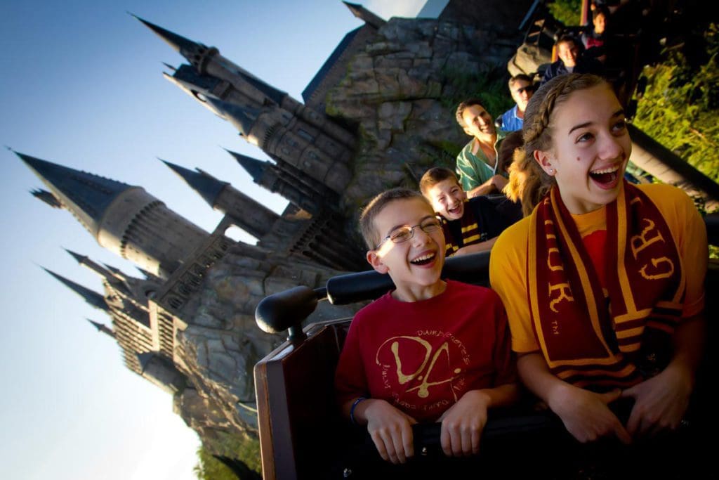 A roller coaster speeds along a track with happy kids on board at the Universal Parks.