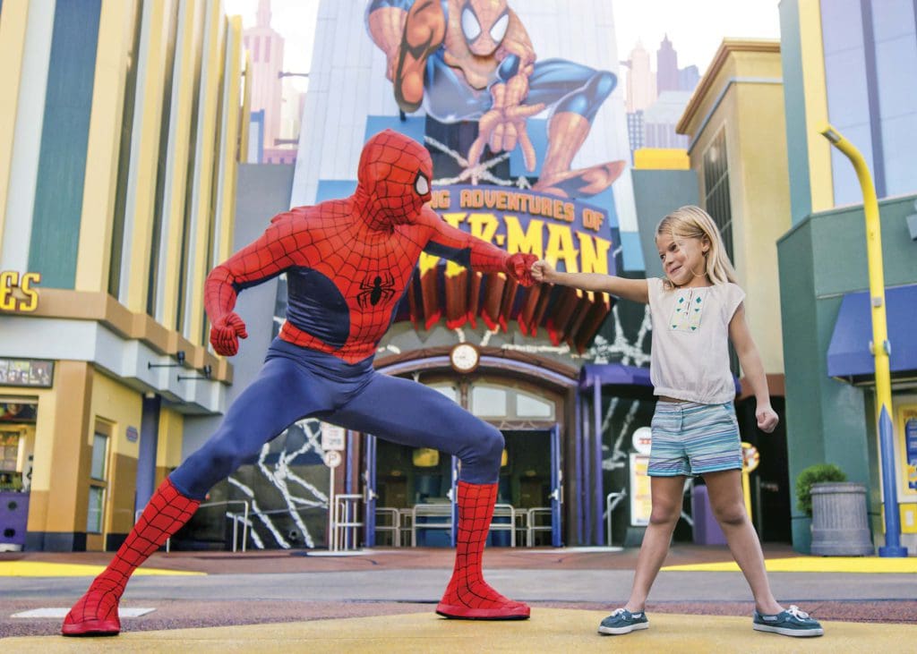 A young girl holds out a hand to Spiderman, who does the same at Universal Orlando.