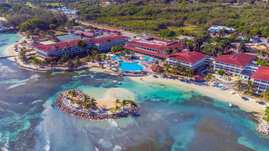 An aerial view of the Holiday Inn Montego Bay, featuring a long beach and lush foliage.