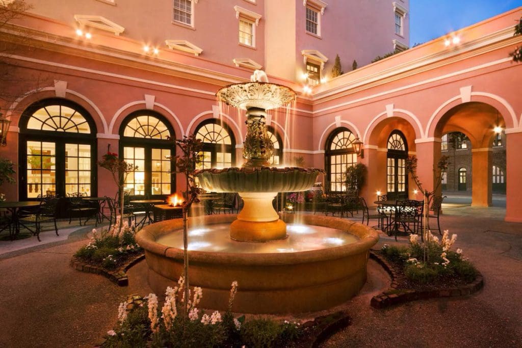 The interior courtyard of The Mills House Wyndham Grand Hotel, featuring a large, stone fountain.