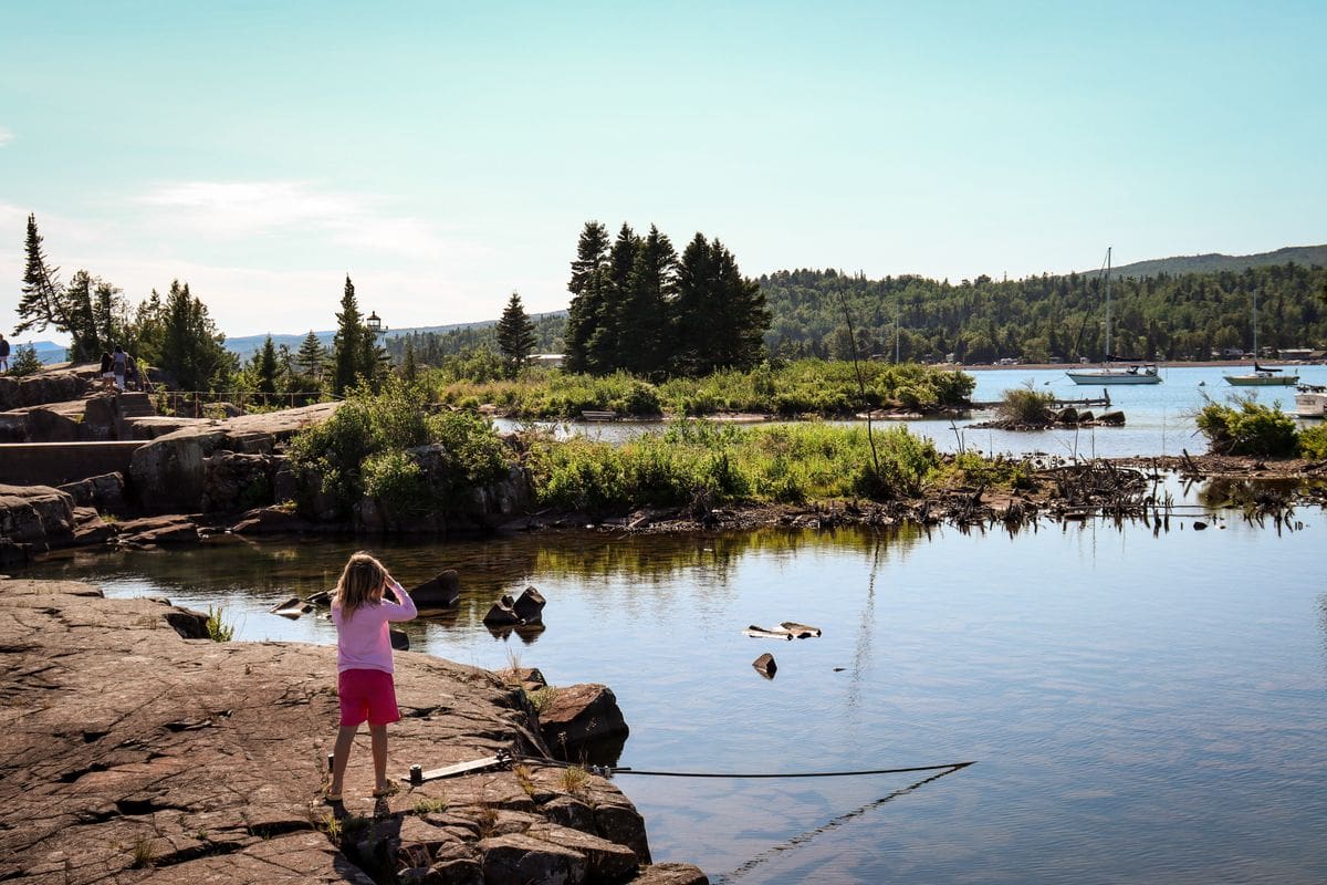 A young girl looks into Lake Superior while exploring Grand Marais, one of the best places to visit in northern Minnesota with kids.