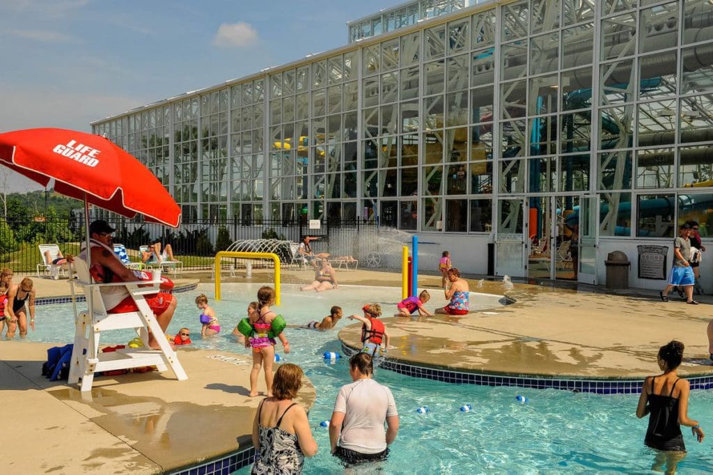 People are enjoying the outdoor pool on a sunny day at Big Splash Adventure, with the resort building in the background.