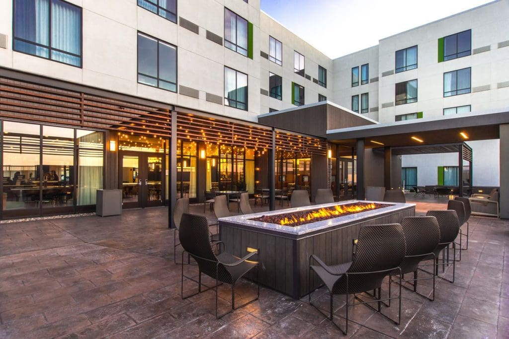 The rear exterior of Courtyard by Marriott, Rapid City, SD, featuring a large bonfire area with chairs surrounding it.