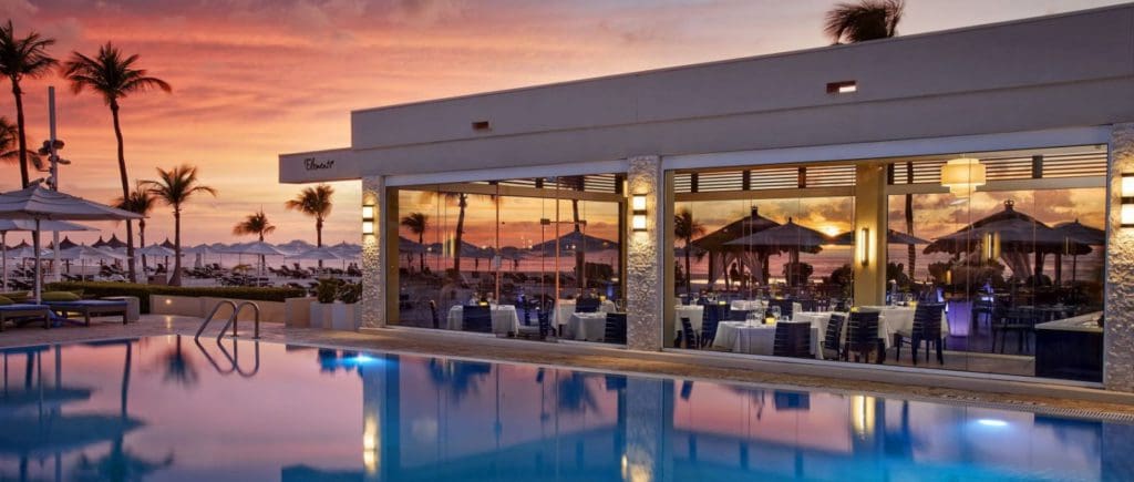 The exterior of the open-air restaurant, Elements Restaurant at Bucuti & Tara Beach Resort, across a peaceful pool, one of the best restaurants In Aruba for families.