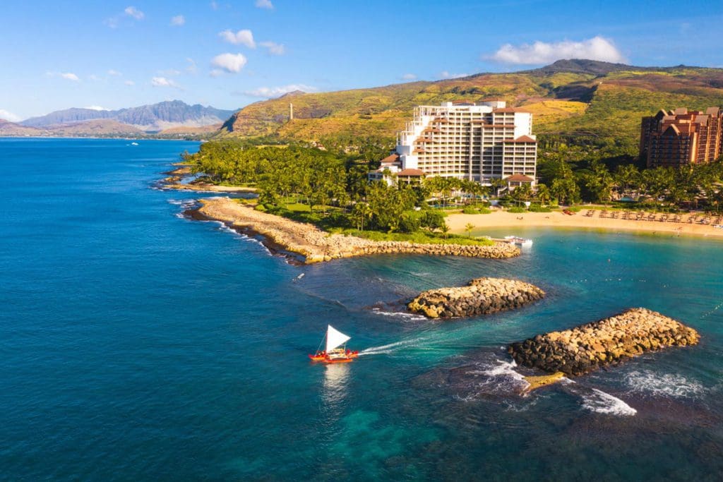 An arial view of Four Seasons Resort O'ahu Ko Olina, featuring a sprawling beach and lush resort grounds.