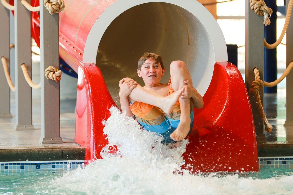 A young boy slides down a large water slide at Grand View Lodge Spa & Golf Resort, one of the best places to explore near the Twin Cities with kids.