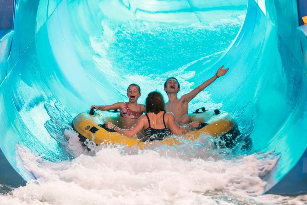 Three people in a large yellow innertube rush down a water slide at Photo Courtesy: Great Wolf Lodge in the Wisconsin Dells.