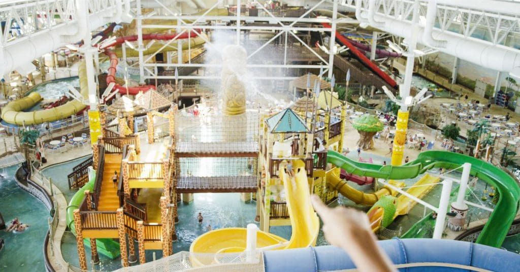 An aerial view of the indoor water park at Kalahari Resort, featuring colorful slides and sprays of water.