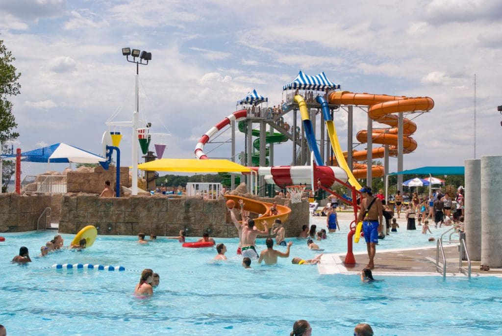 Several kids and adults explore the waters of the outdoor water park at Photo Courtesy: King's Pointe Resort, featuring several large water slides.