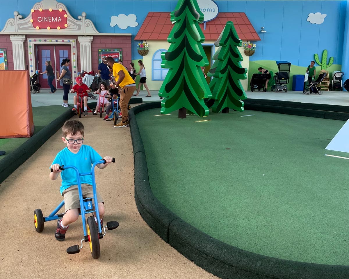 A young boy riding a tricycle races around a track at one of the play areas at the Peppa Pig Theme Park in Florida.