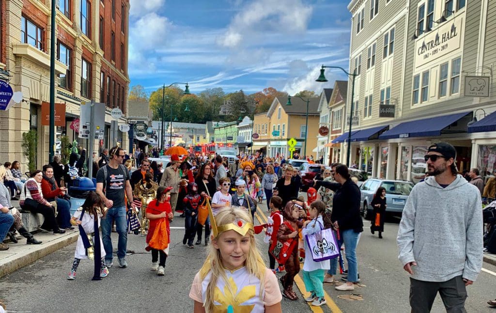 A downtown street in Mystic is filled with costumed children on Halloween.
