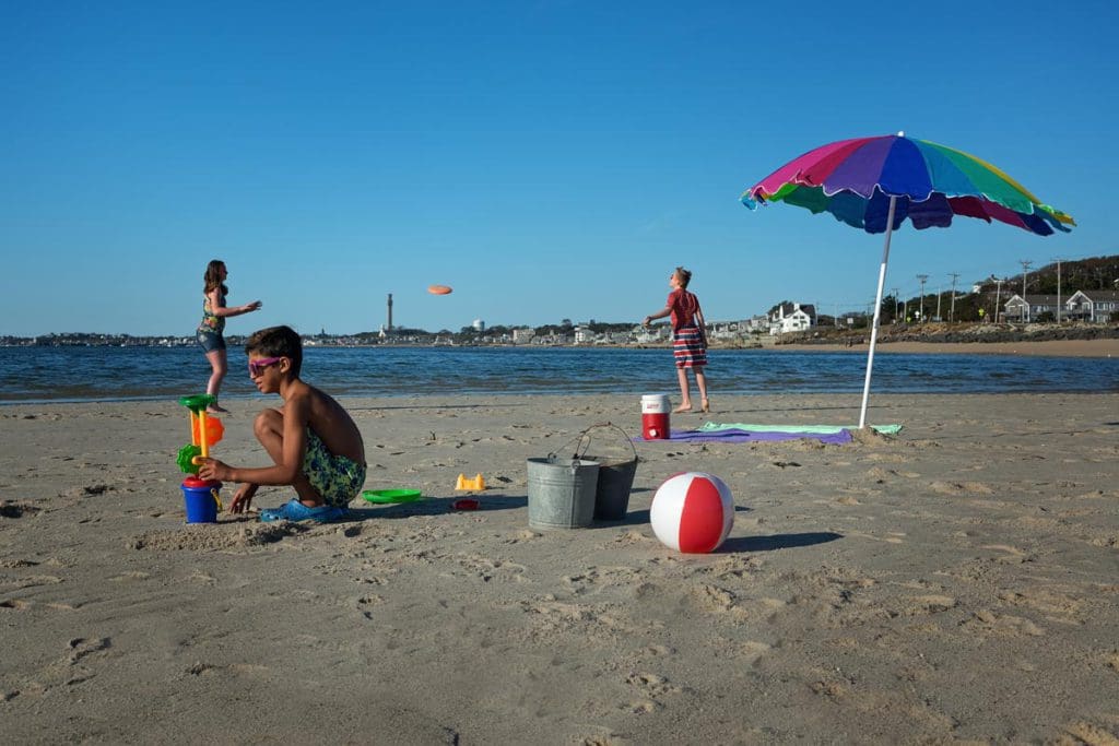 Several kids play on the beach in Provincetown on a sunny day.