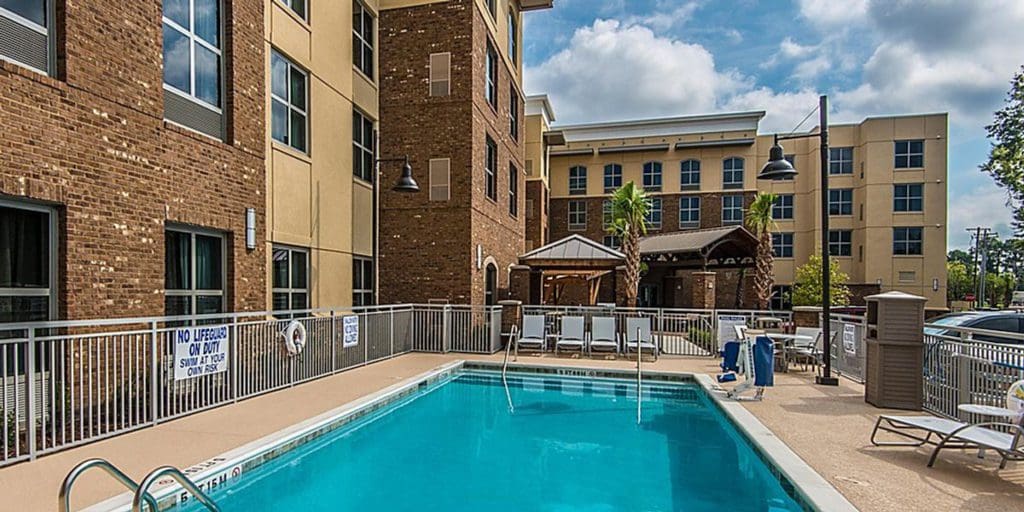 The outdoor pool at Staybridge Suites Charleston - Mount Pleasant, an IHG Hotel, with the hotel building towering directly behind it.