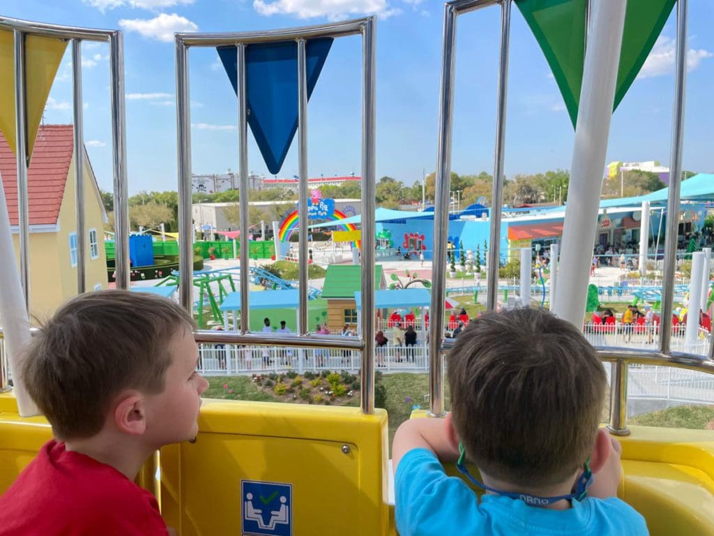 Two kids look out from a high balloon ride out onto a large theme park.
