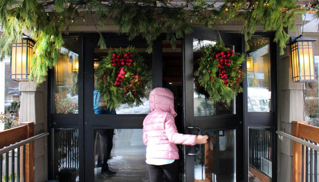 A young girl enters the front doors of the Woodloch Resort, with wreathes on the doors.