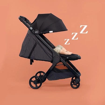 A black Ergo Baby Metro Plus holds a sleeping baby.