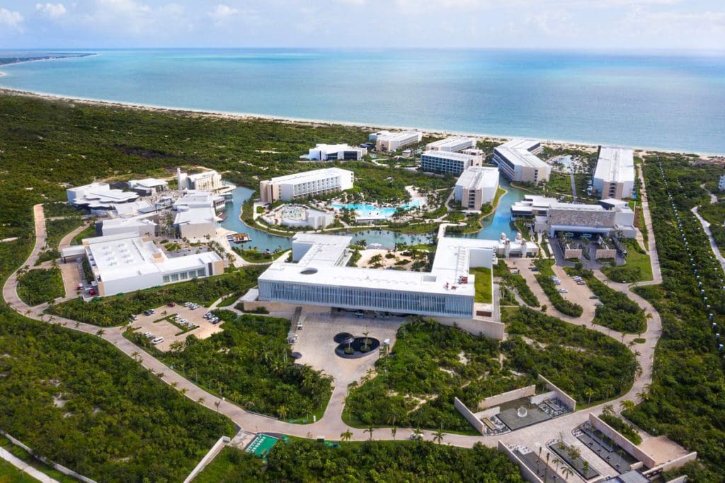 An aerial view of the expansive grounds of Grand Palladium Costa Mujeres Resort & Spa, featuring several resort buildings and ocean view.